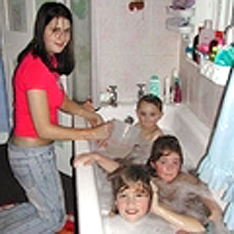 A young woman bathing her three younger siblings.